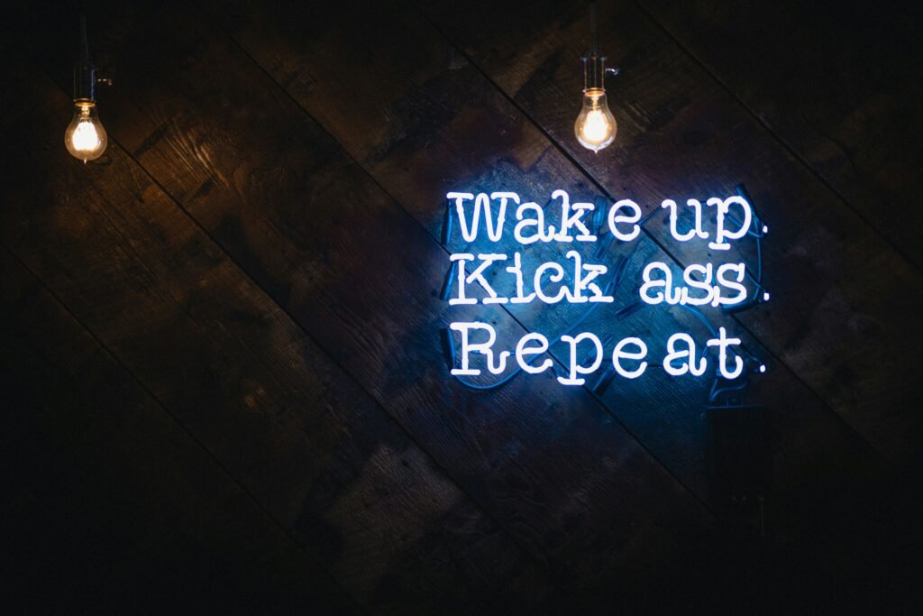 jak pracować nad sobą zdjęcie motywacyjnego napisu na neonie "wake up, kick ass, repeat"